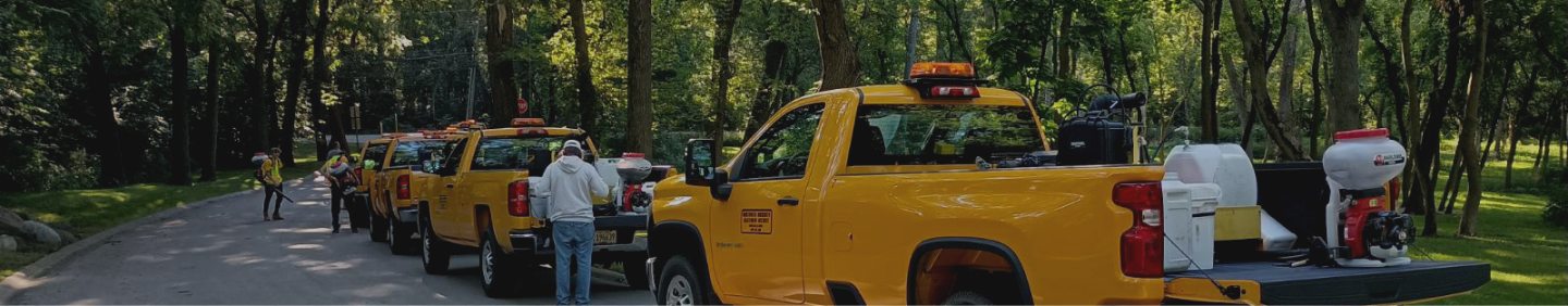 Secondary level page banner image showing mosquito abatement trucks with tailgates down, lined up on a street. 